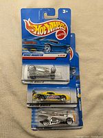 Three Hot Wheels cars stacked: Deuce Roadster, yellow racer, Dogfighter
