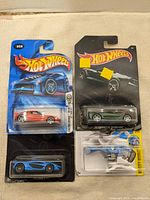 Four sealed Hot Wheels blister packs on surface