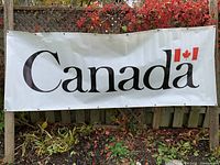 Full view of white vinyl banner displaying "Canada" wordmark with flag