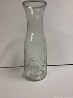 Full view of clear textured glass carafe showing flower design