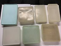 Seven Tupperware containers arranged in two rows showing variety of sizes and colors