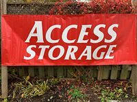 Front view of red "ACCESS STORAGE" banner displayed on fence