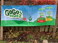 Full view of banner hung on fence showing GoGo Squeez logo and pouch graphics