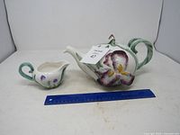 Teapot on side and creamer with ruler for scale