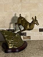 Full view of metal deer figurine on wood base