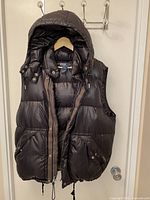 Front view of black hooded puffer vest on hanger