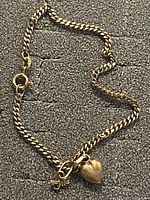 Full view of bracelet laid flat, showing curb links and charms