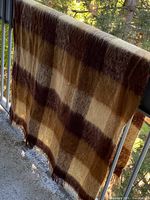 Full view of blanket draped over railing showing color pattern and fringe