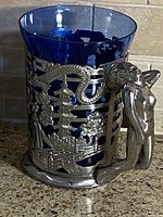 Front view showing cobalt glass liner and metal overlay with dragon, pagoda, bridge, floral motifs