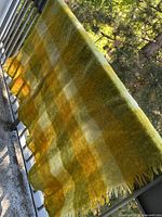 Full view of plaid throw hanging on railing