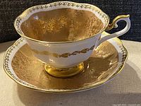 Teacup on saucer showing gold chintz interior and exterior decoration