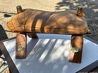 Overall view of camel saddle stool showing leather cushion and wood base