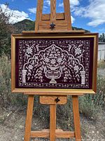 Full view of framed silver wire art on easel