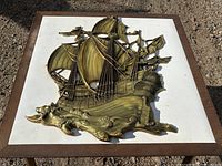 Full view of gold-tone Syroco sailing ship plaque on white surface