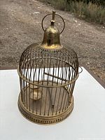 Full view of brass birdcage showing wires, base and hanger