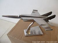 Left front view of polished aluminum fighter jet on stand