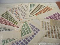 Spread of multiple full Canadian stamp sheets in sleeves showing various colours and denominations