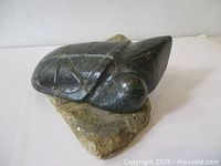 Full side view of stone turtle sculpture on rock base
