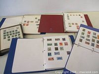 Five albums open showing pages of mounted stamps