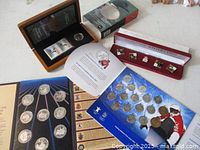 Overview of all four presentation sets opened showing coins, stamps and pins