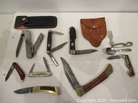 Group shot of seven folding knives, leather sheaths, BSA utensil set