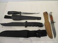 Three knives with respective sheaths laid out