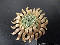 Front view showing sunburst design and green rhinestone cluster