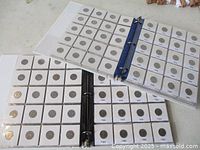 Two open binders showing multiple vinyl sheets of carded nickels