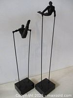 Both metal acrobat sculptures on marble bases full view