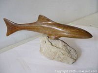 Left side view of carved wooden shark on rock base