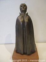 Front view of bronze cloaked woman sculpture on wood base