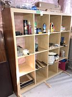 Front view of entire 4x4 cubby shelf showing 16 cubbies and light wood laminate with darker sides