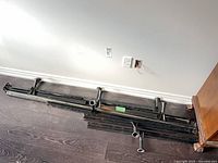 Stack of disassembled black steel bed frame rails and legs on floor