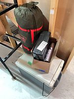 Cooler, sleeping bag in compression sack, tool case and box of accessories stacked together