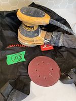 Sander, dust bag, sanding disc on surface