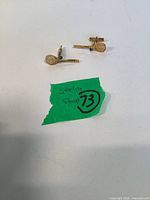 Pair of gold-tone tennis racket cufflinks on white surface