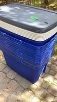 Stack of blue plastic bins with grey lids visible