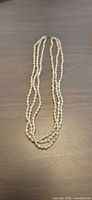 Full view of three-strand freshwater rice pearl necklace laid flat