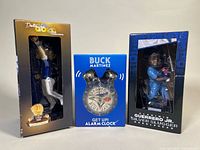 Front view of three boxed items: Guerrero Jr. Silver Slugger bobblehead, Buck Martinez alarm clock, Varsho Gold Glove bobblehead