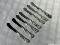 All seven butter knives laid out to show full view and size