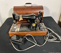 Overall view of sewing machine on base with cover, pedal and cords
