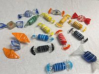 Group shot of 16 glass candy pieces on white fabric