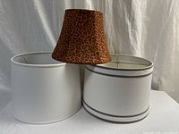 Front view showing all three lampshades: two white drum shades and one leopard print bell shade