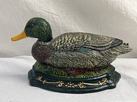 Full view of painted cast metal duck door stop on decorative base