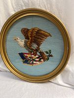 Front view of round framed needlepoint showing eagle on flag