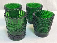 Group shot of four emerald green tumblers; three hobnail, one swirl pattern