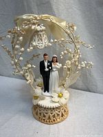 Full view of cake topper showing couple, arch, ribbon, floral details and base