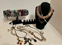 Group shot showing necklaces laid out, bracelets on bar and rings on stand