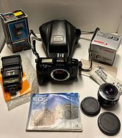 All items laid out: camera body, lens, flash, case, manuals, boxes, caps