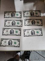 Obverse of seven $2 bills showing sequential serial numbers and green seals